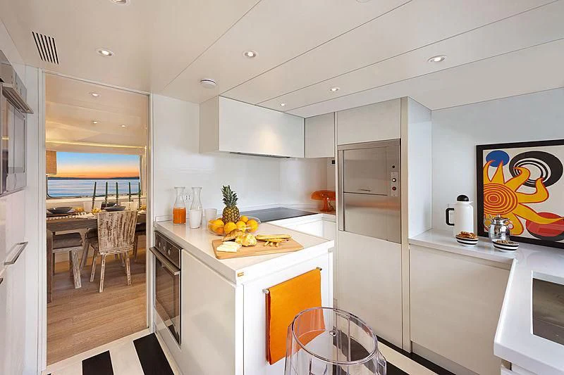 a kitchen with white cabinets and a table with fruit on it aboard VERVECE Yacht for Charter