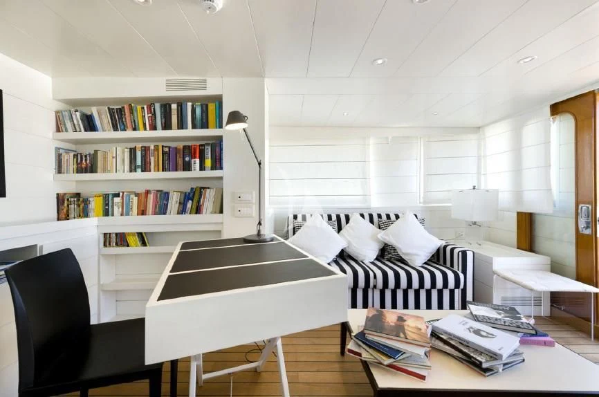 a living room with a black chair and a white table aboard VERVECE Yacht for Charter