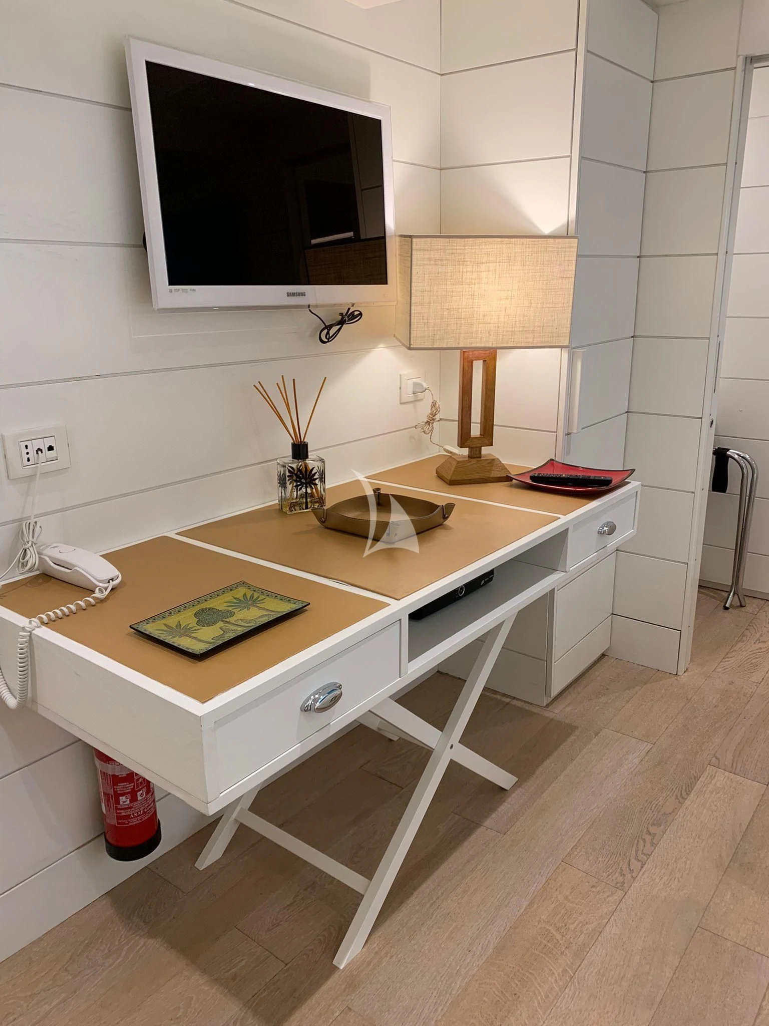 a white kitchen with a flat screen television and white tile walls aboard VERVECE Yacht for Charter
