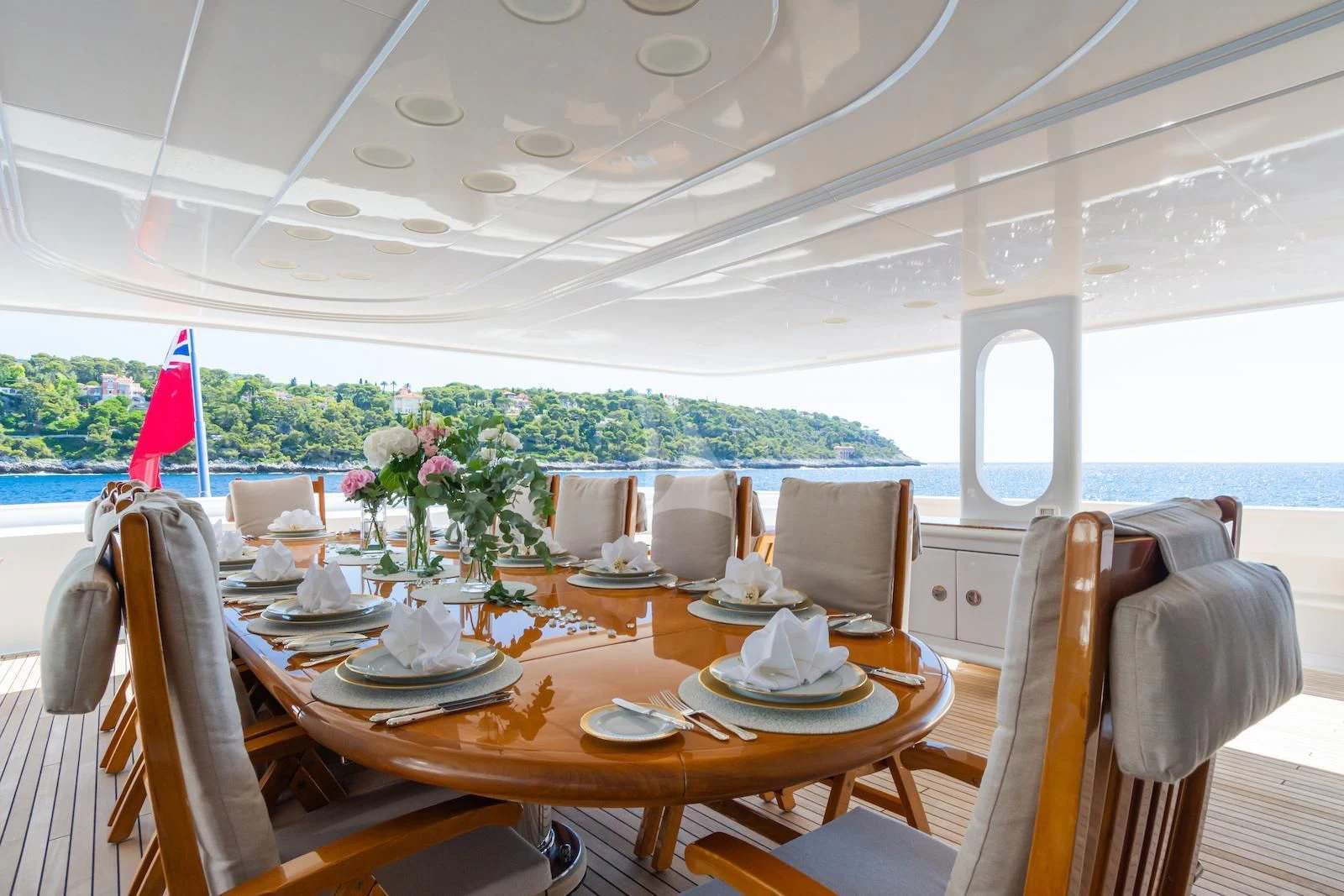 a dining table with chairs and a large window with a view of the water aboard APOGEE Yacht for Sale