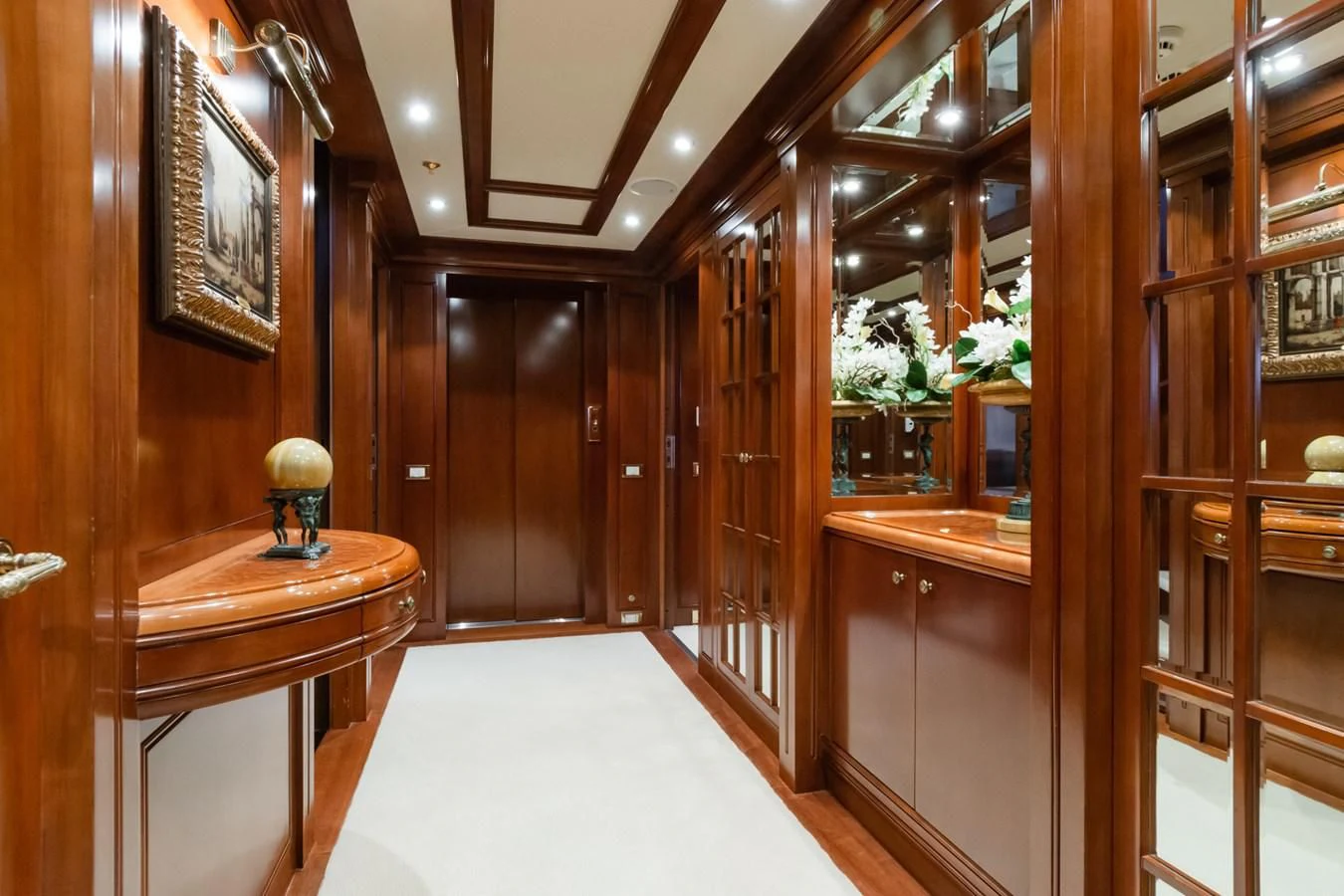 a room with wooden cabinets and a table and a vase on a table aboard APOGEE Yacht for Sale