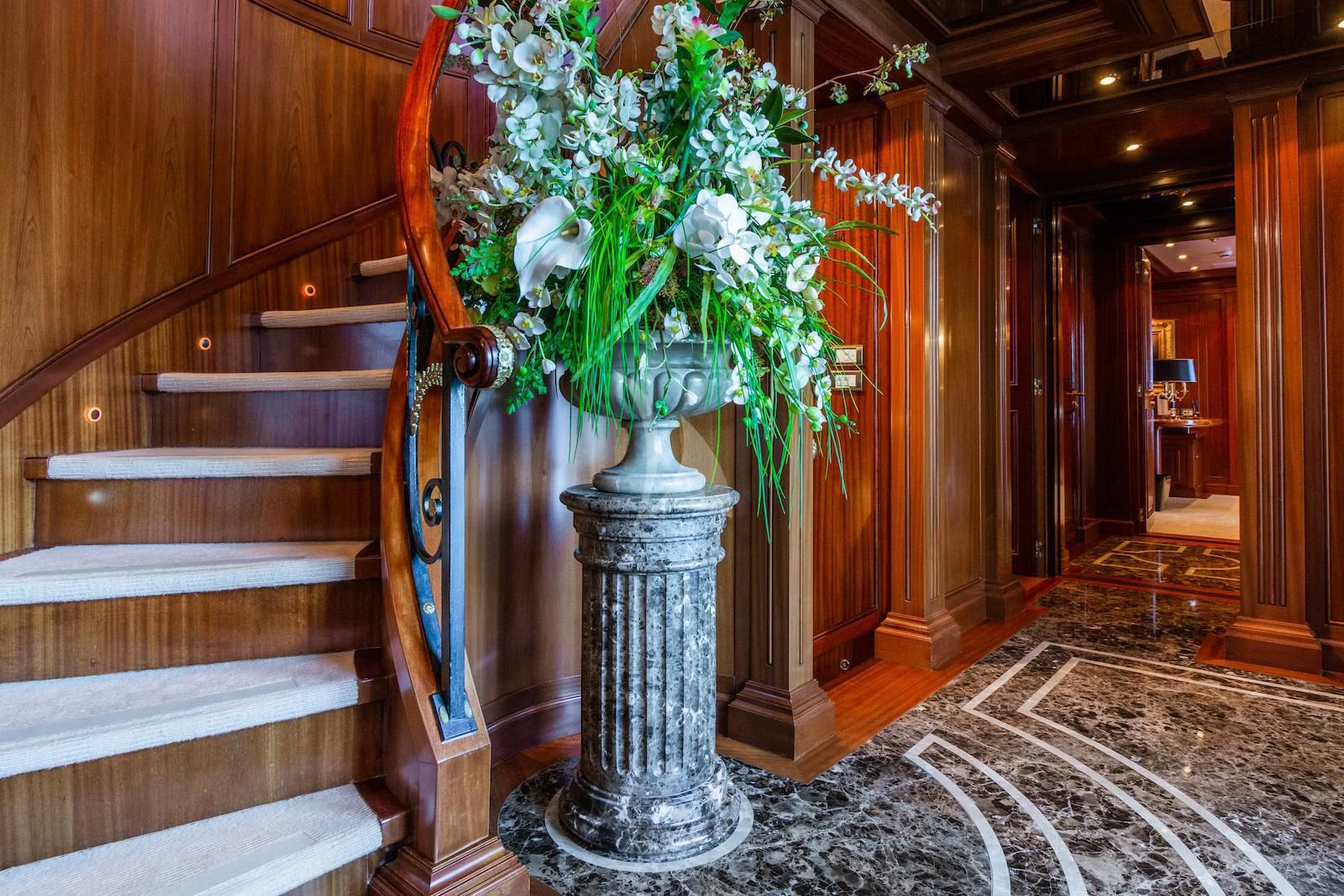 a vase with white flowers in a room with a staircase aboard APOGEE Yacht for Sale