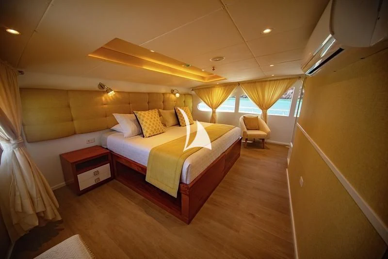 a room with a bed and a chair aboard GRAND DAPHNE Yacht for Charter