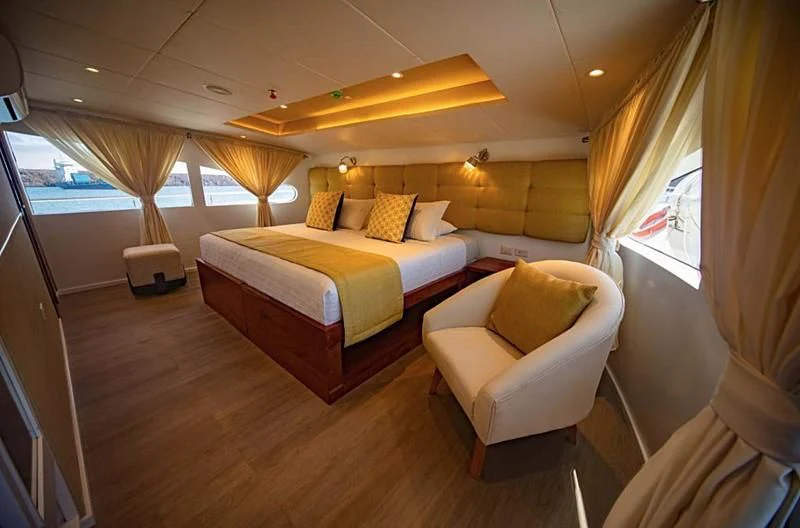 a room with a bed and a chair aboard GRAND DAPHNE Yacht for Charter