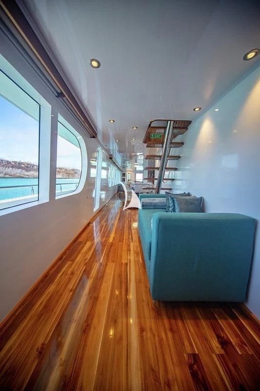 a long wood deck with a blue couch and a large window aboard GRAND DAPHNE Yacht for Charter