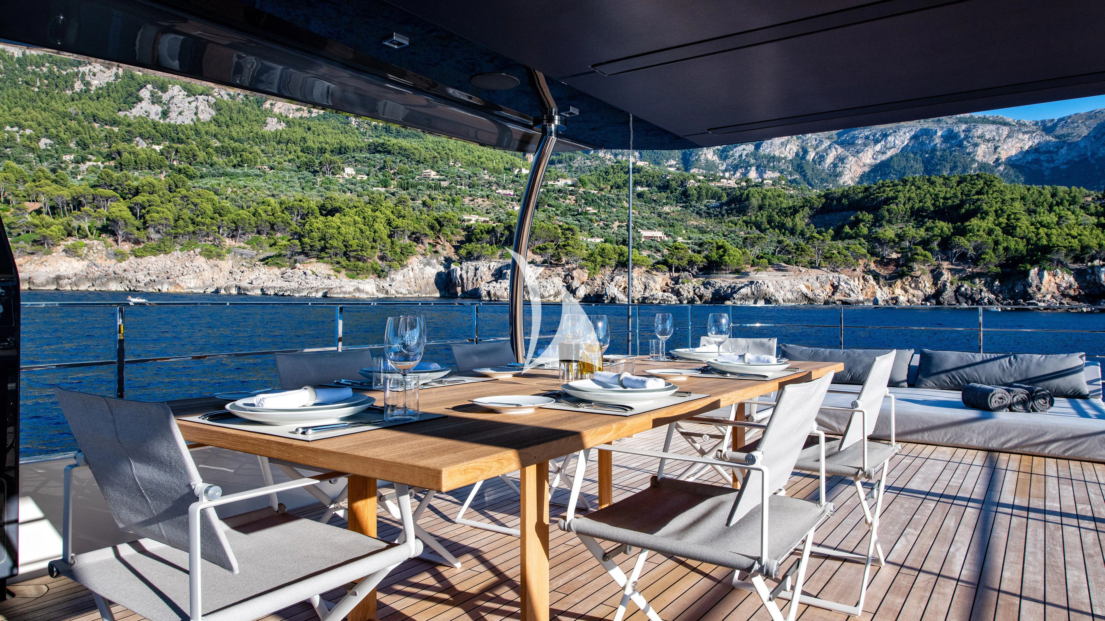 a table and chairs on a deck overlooking a body of water aboard PALOMA Yacht for Sale