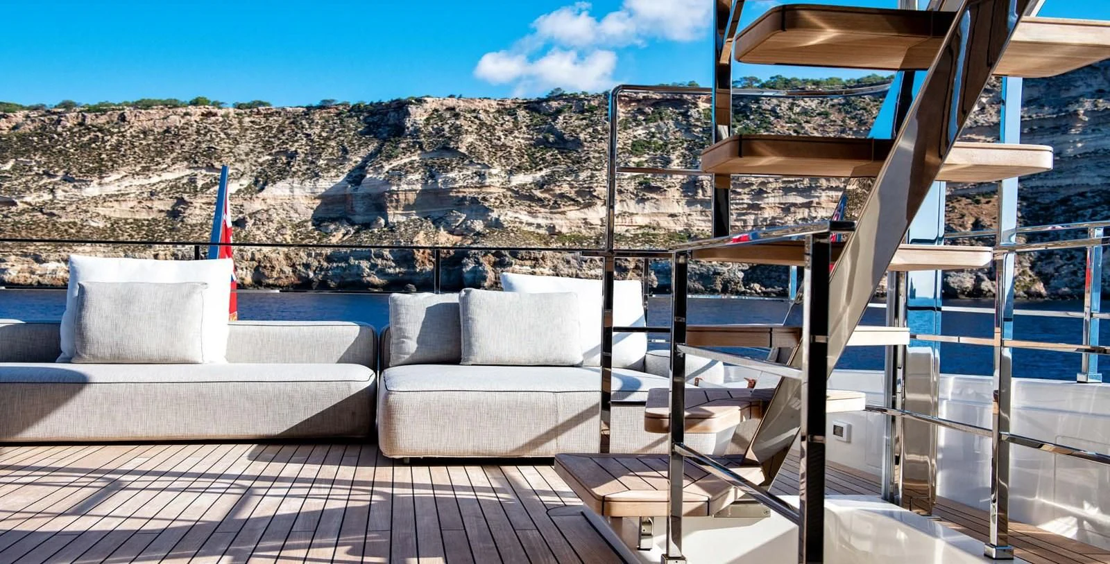 a deck with a couch and a view of a mountain range aboard PALOMA Yacht for Sale
