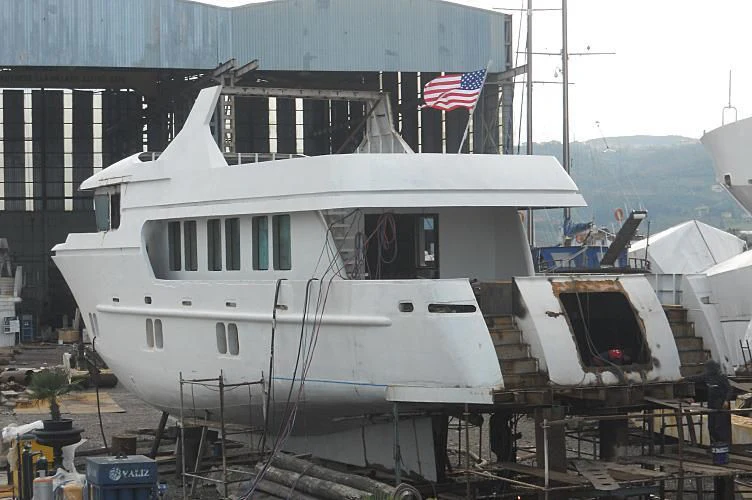 a large white boat with a flag on the front aboard APRIL V Yacht for Sale