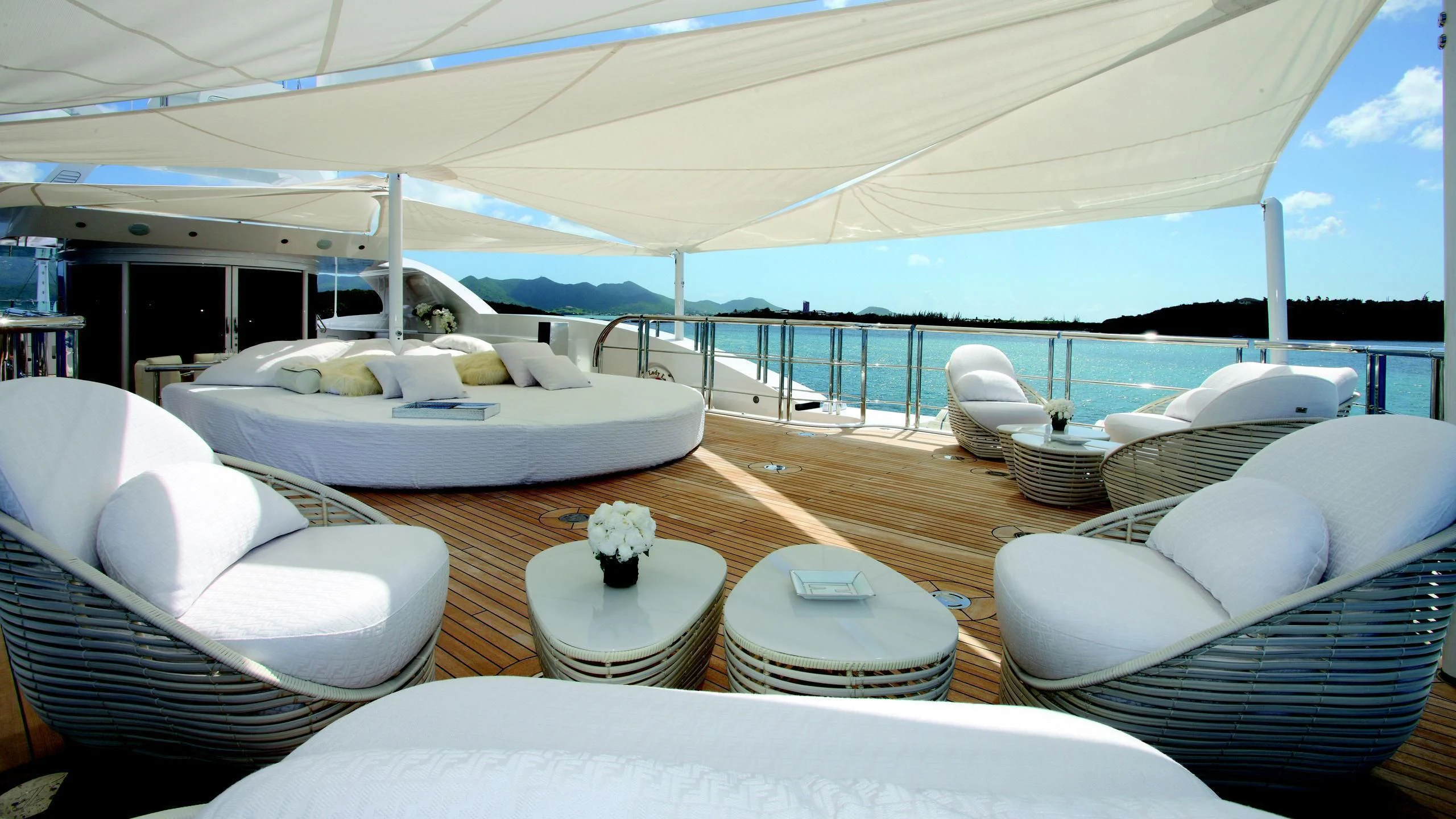 a large white lounge chair on a deck with a large white bed and white pillows and a white aboard MONARCH Yacht for Sale