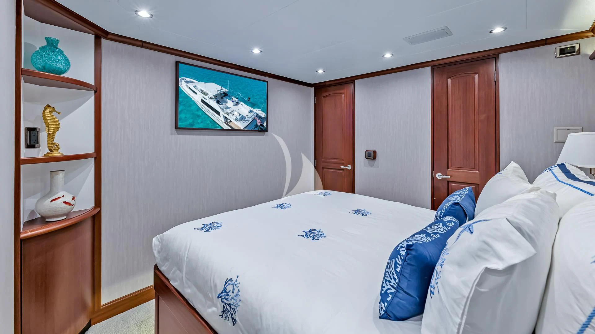 a room with a bed and a shelf with objects on it aboard LADY B Yacht for Charter