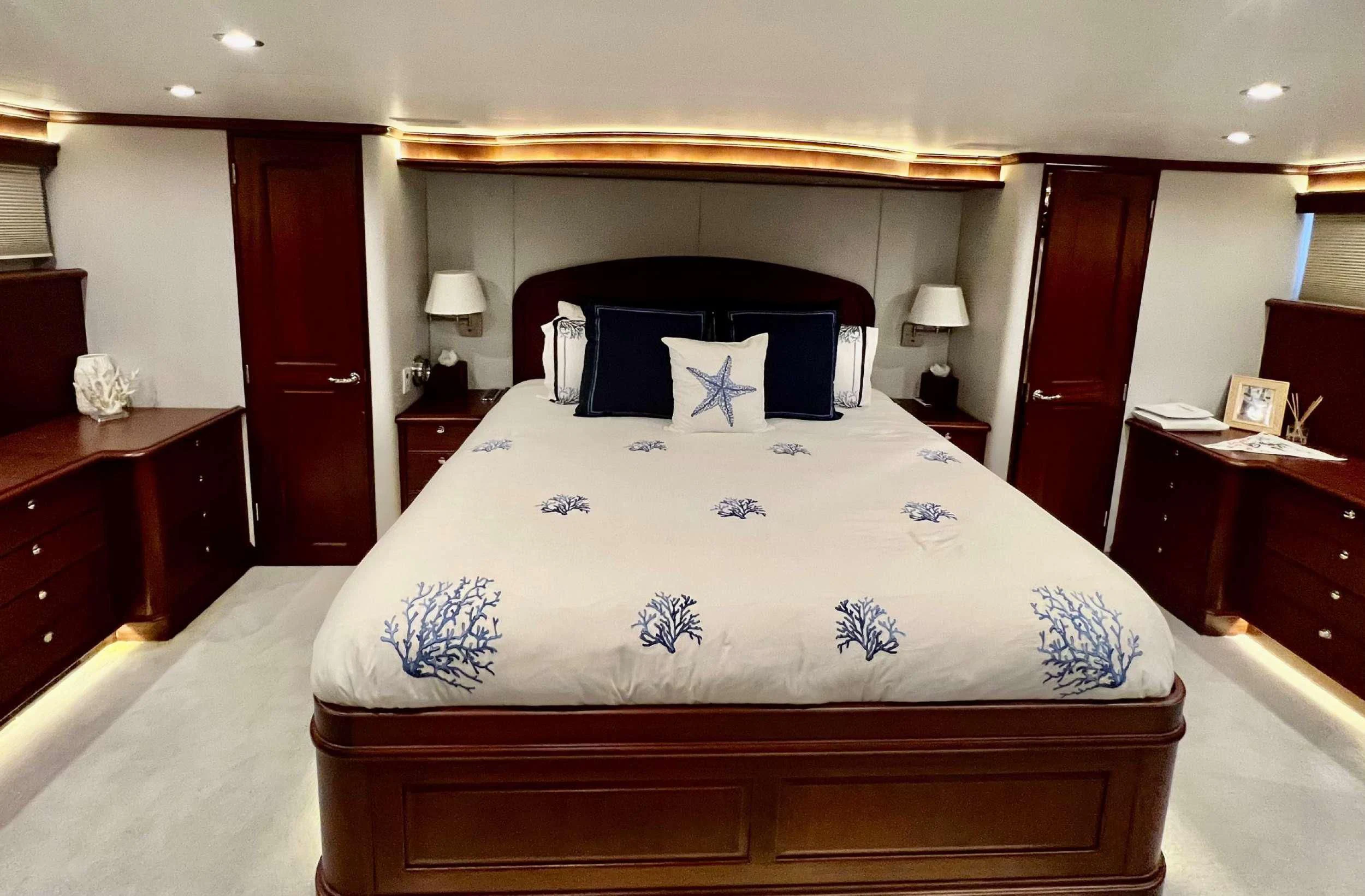 a bed with a blue and white comforter and pillows aboard LADY B Yacht for Charter