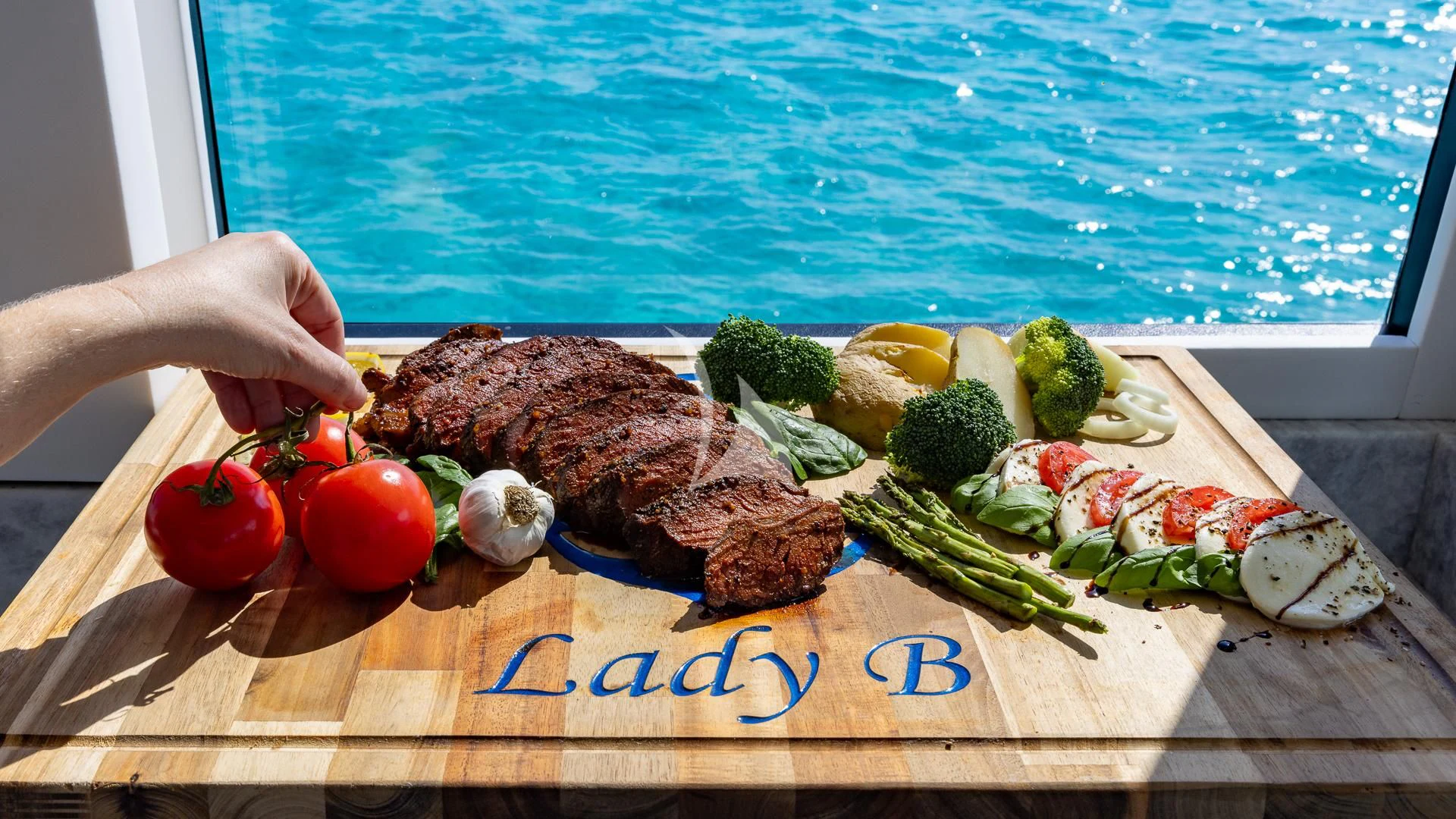 a person cutting a board with food aboard LADY B Yacht for Charter