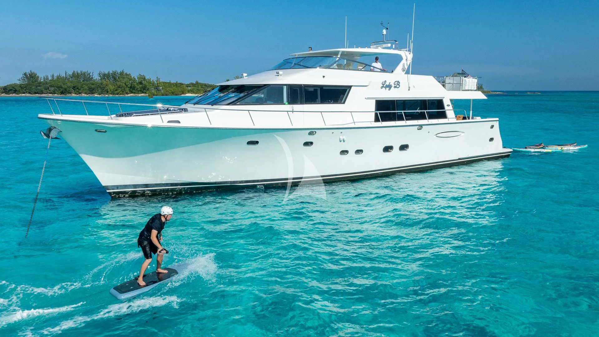 a person on a surfboard in the water next to a boat aboard LADY B Yacht for Charter