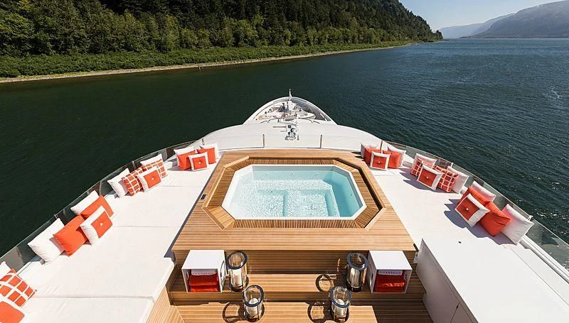a large white boat with orange and red containers on a dock aboard CHASSEUR Yacht for Charter