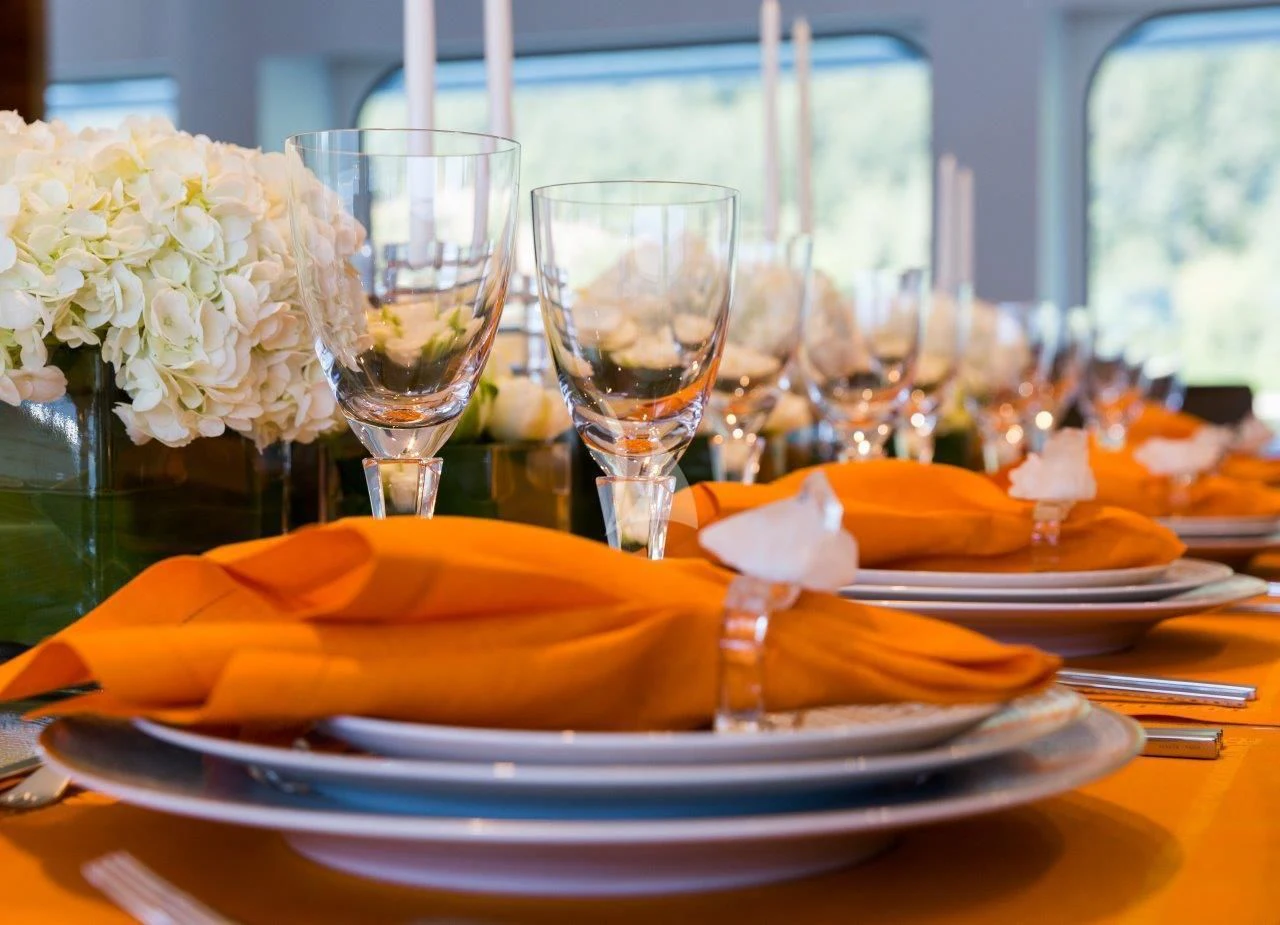 a table with plates and glasses of wine aboard CHASSEUR Yacht for Charter