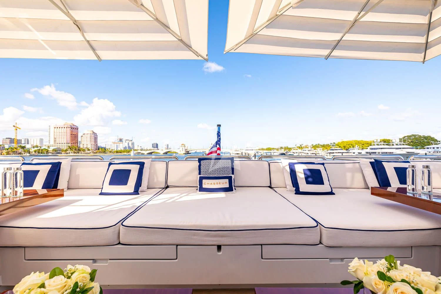 a large white boat with blue and white windows and a city in the background aboard CHASSEUR Yacht for Charter