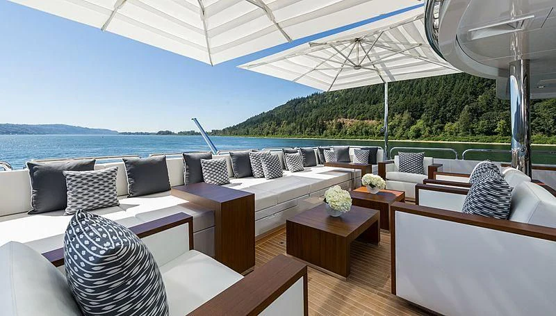 a large white lounge chair next to a large white umbrella on a patio aboard CHASSEUR Yacht for Charter