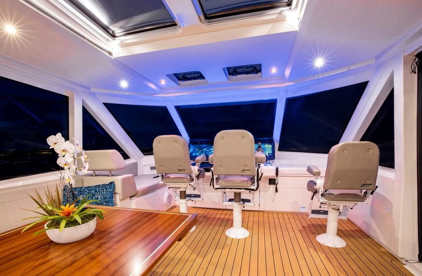 a room with a table chairs and a wood floor aboard PLANE TO SEA Yacht for Sale