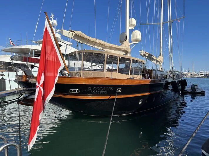 a boat with a red and black sail on the water aboard ROXANE Yacht for Sale
