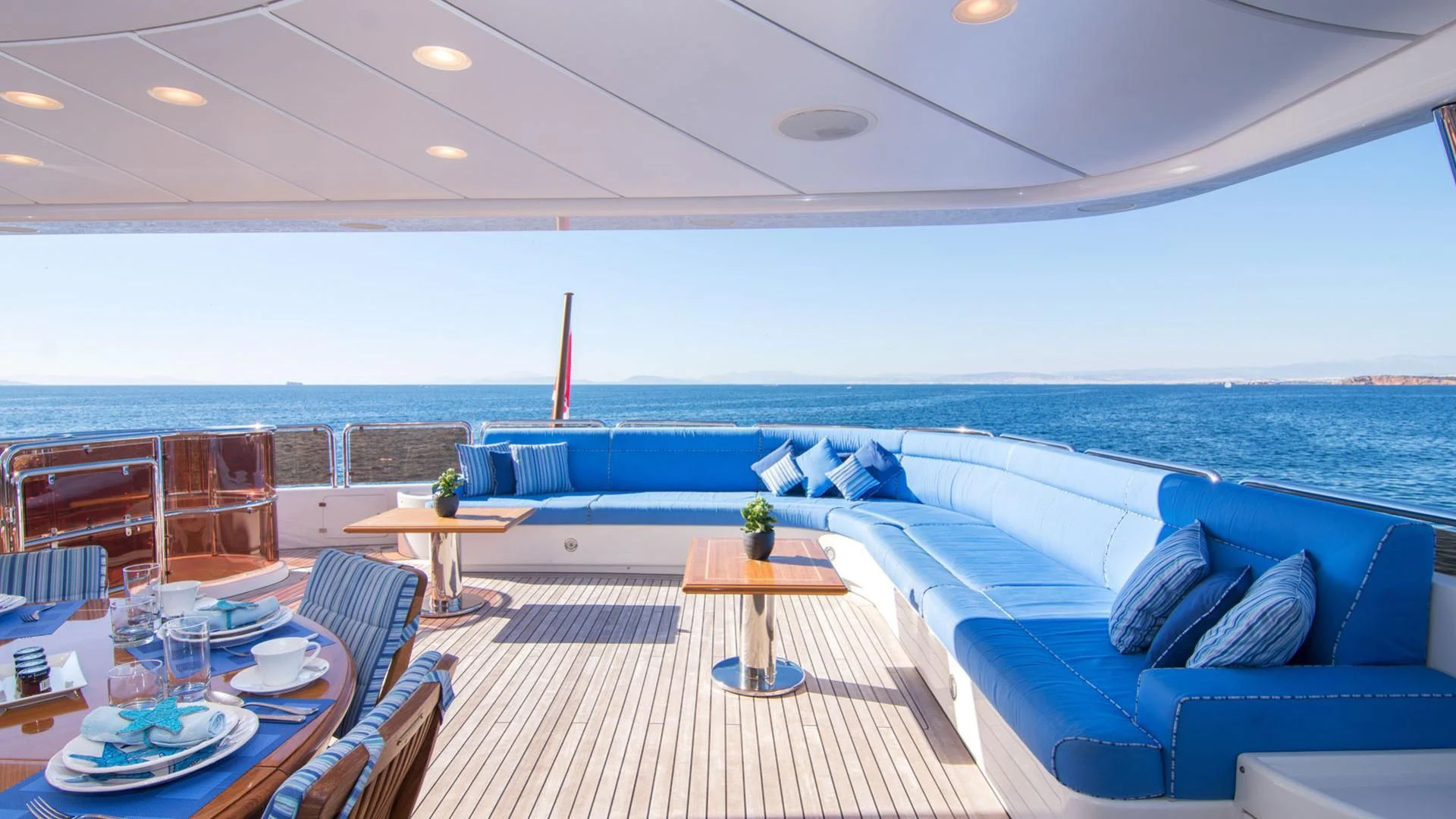 a large lounge area with a table and chairs and a large body of water aboard OPTION B Yacht for Charter