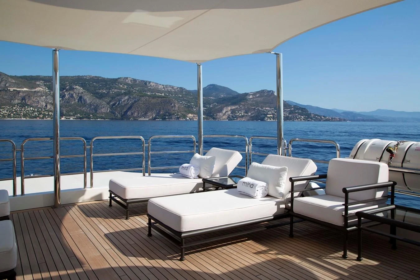 a deck with chairs and a body of water in the background aboard MINA Yacht for Sale
