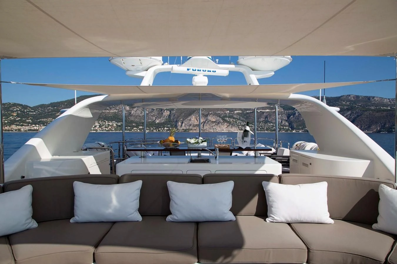 a large lounge area with a pool and a large yacht in the background aboard MINA Yacht for Sale