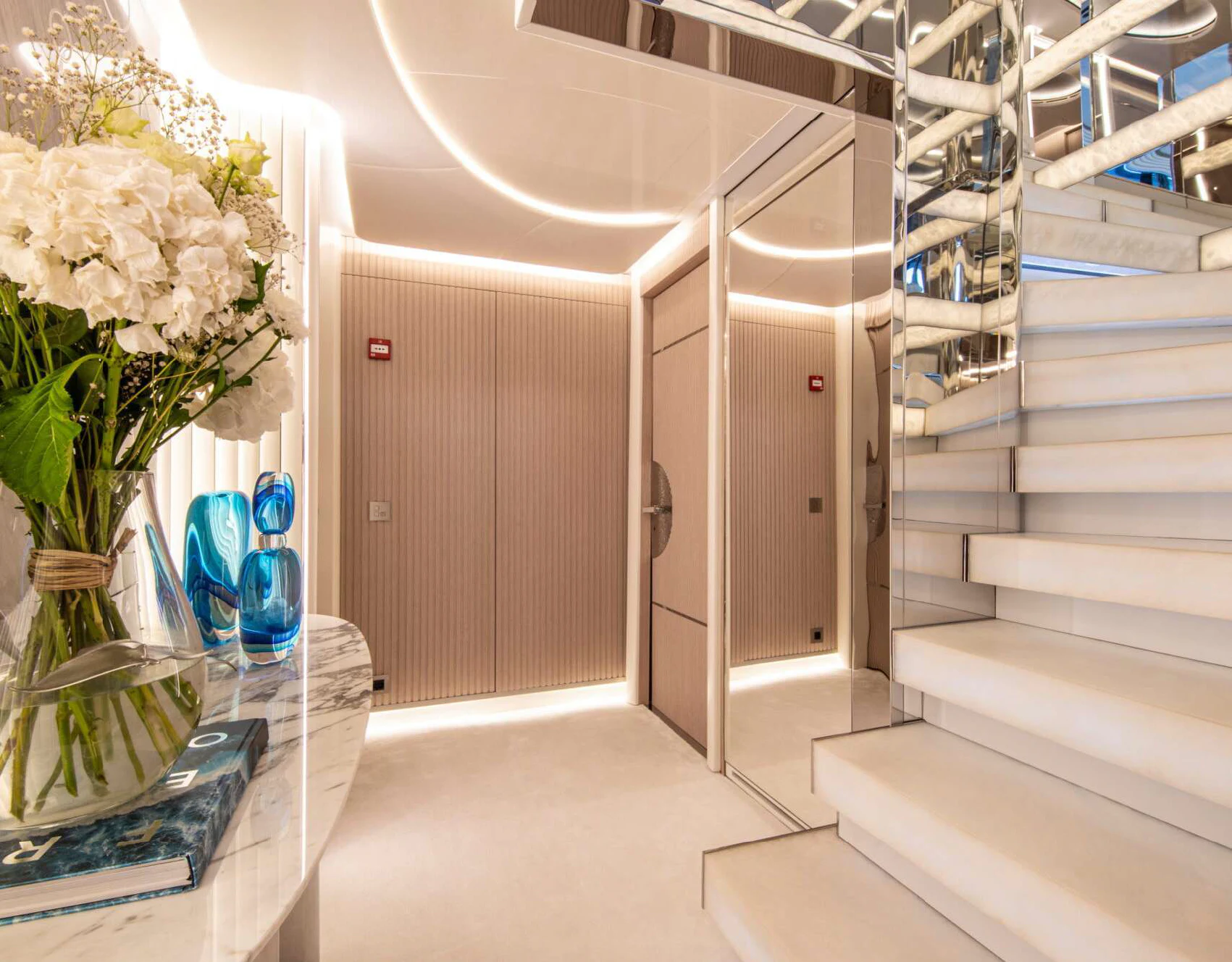 a white staircase with vases of flowers in a room with white walls aboard OCEANBIRD Yacht for Sale