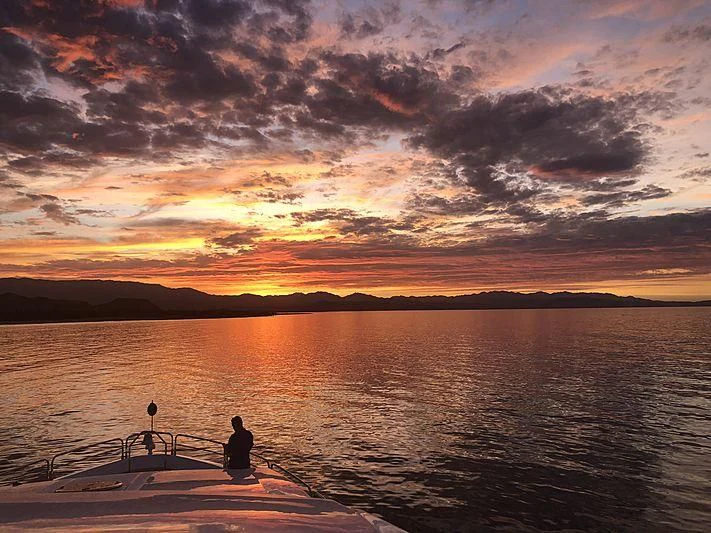 a person sitting on a dock at sunset aboard EMRYS Yacht for Sale
