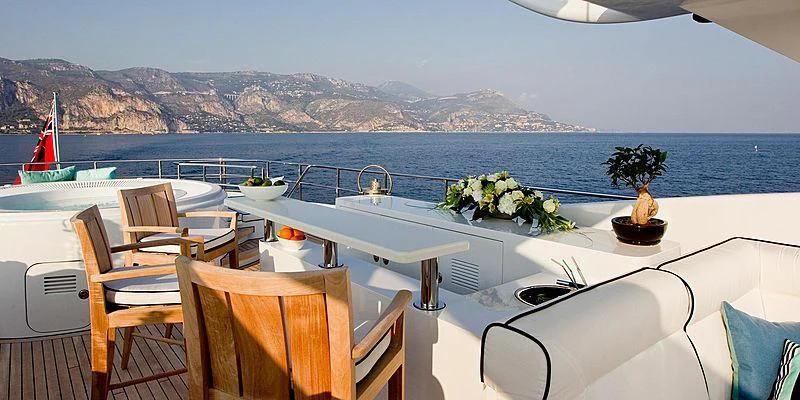a table with chairs and plants on it by a body of water aboard AILISH V Yacht for Sale