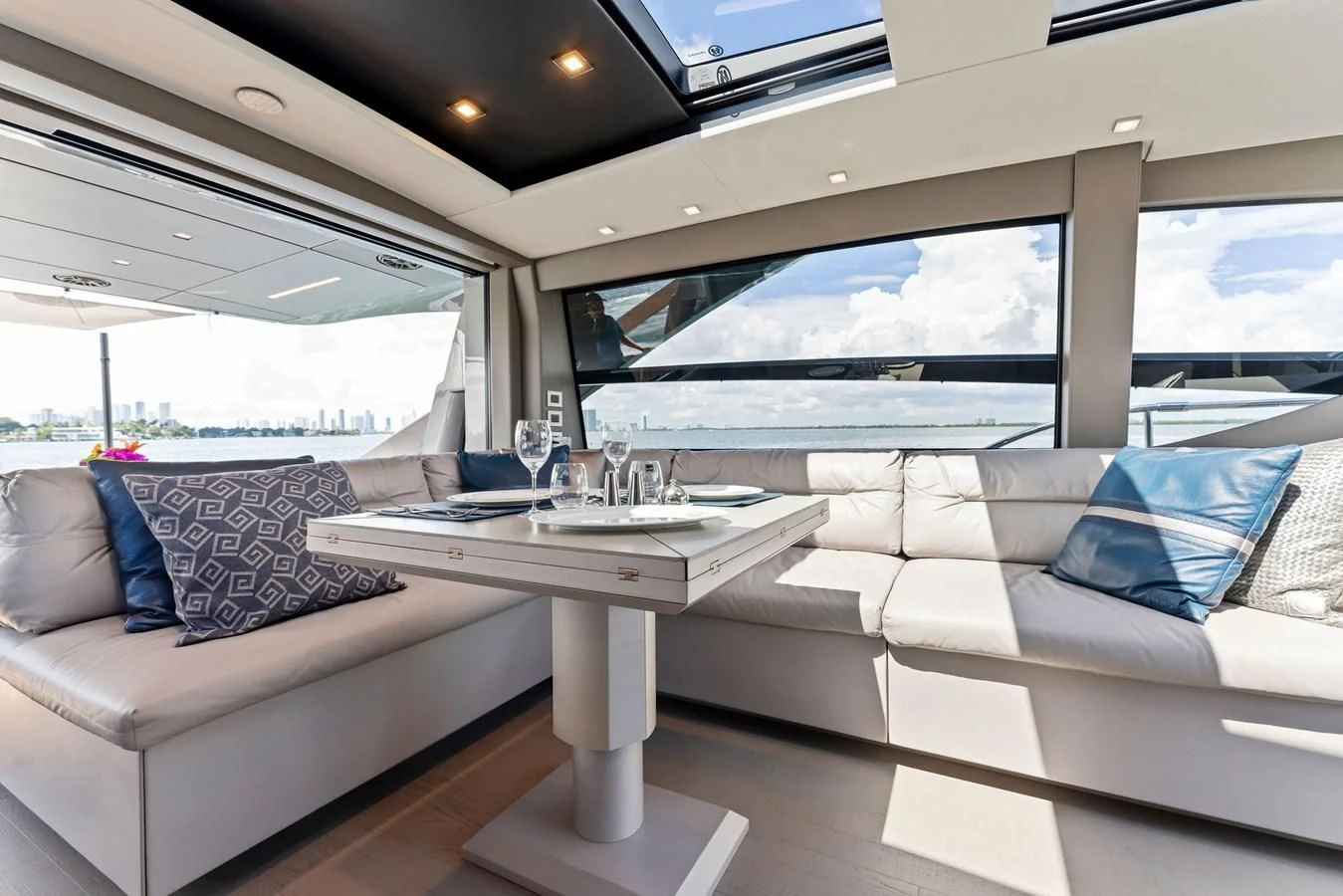 a white couch and a table in a room with a large window aboard PERSHING 7X Yacht for Sale