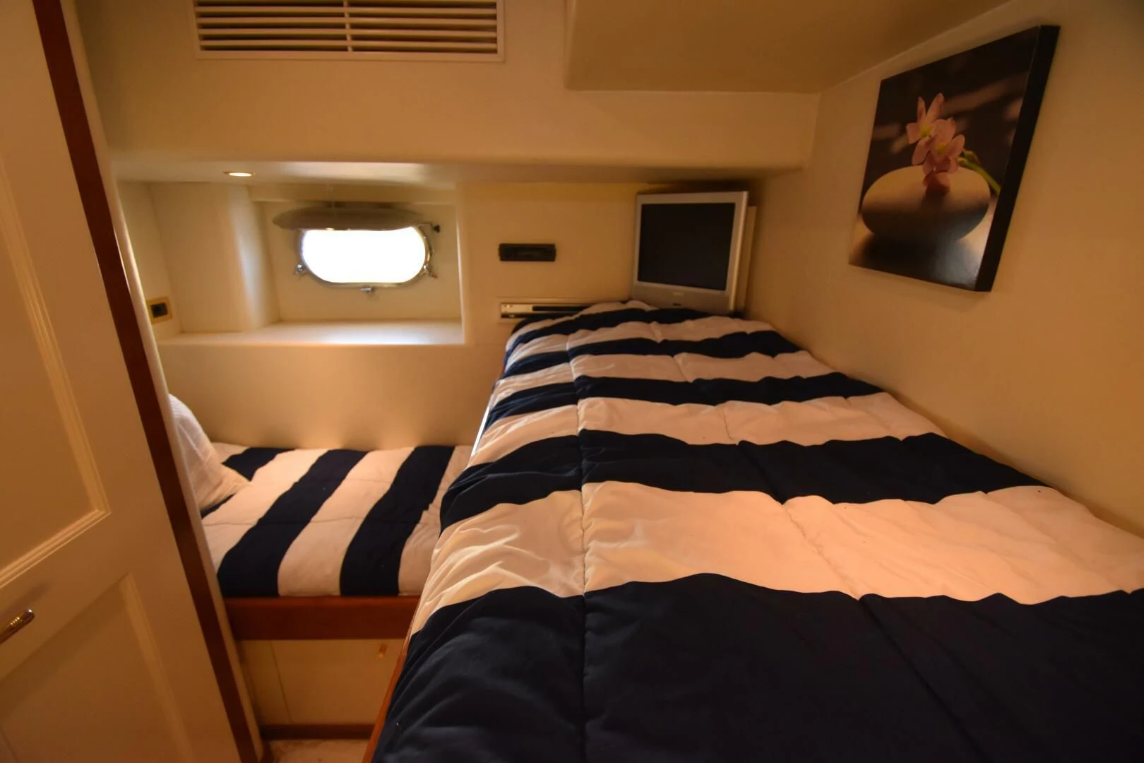a bed with a black and white striped comforter and a white wall aboard BLUE SEAS Yacht for Sale