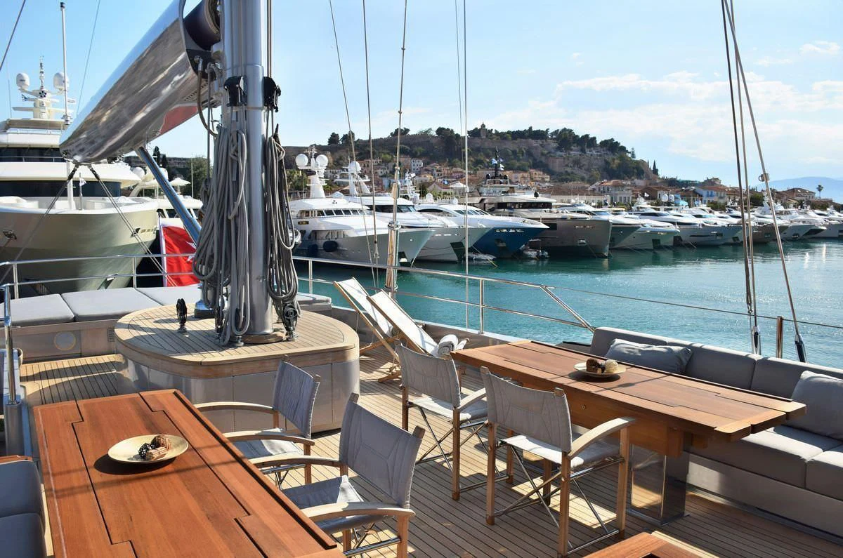 a table and chairs on a deck overlooking a marina aboard BARACUDA VALLETTA Yacht for Sale