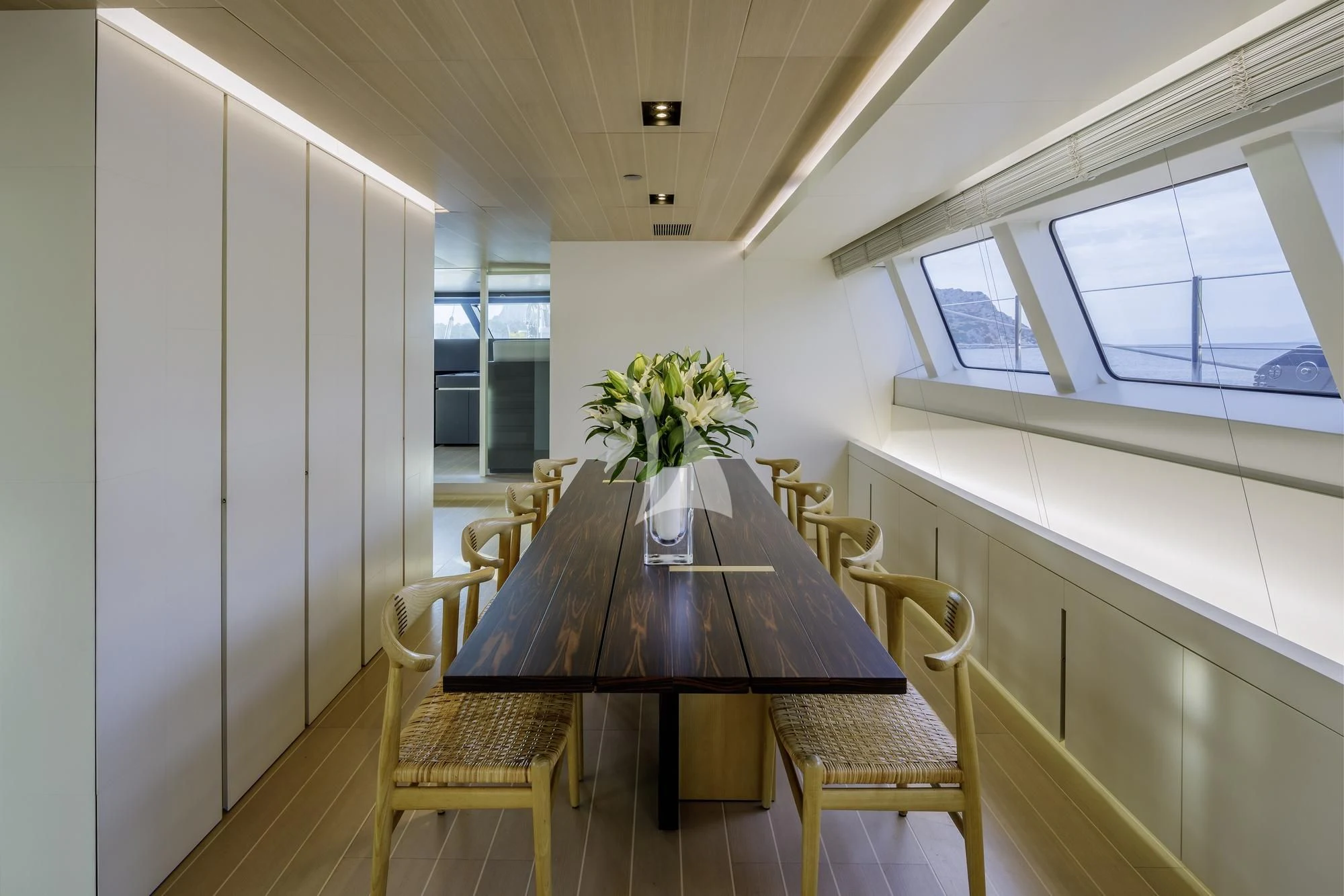 a dining table and chairs in a room with a large window aboard BARACUDA VALLETTA Yacht for Sale