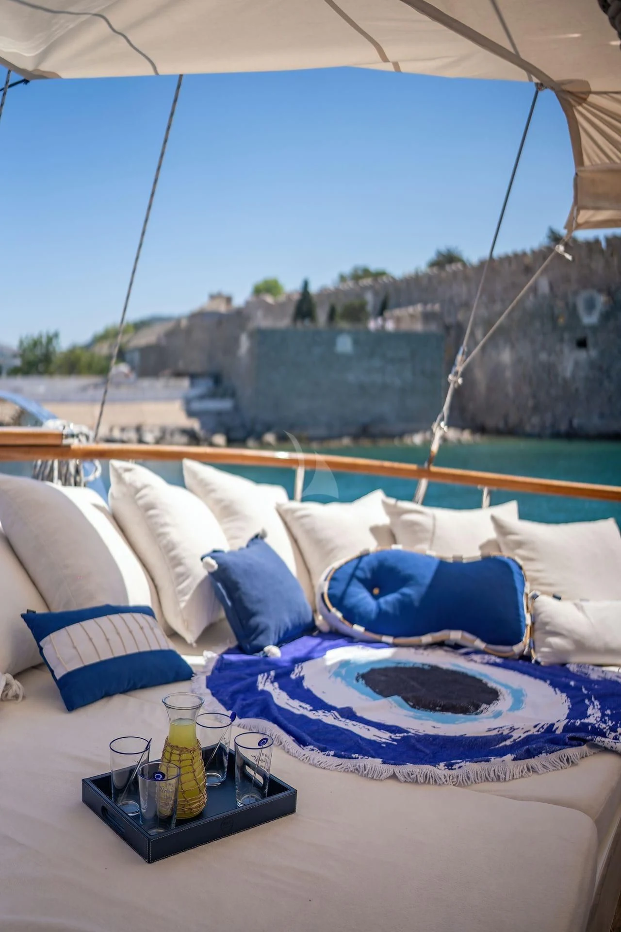 a bed with a blue pillow and a blue pillow on a balcony aboard BABYLON Yacht for Sale