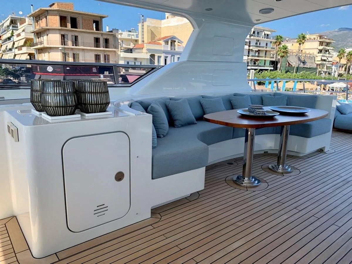 a white rectangular object on a wood surface with a table and chairs aboard MOCEAN Yacht for Sale