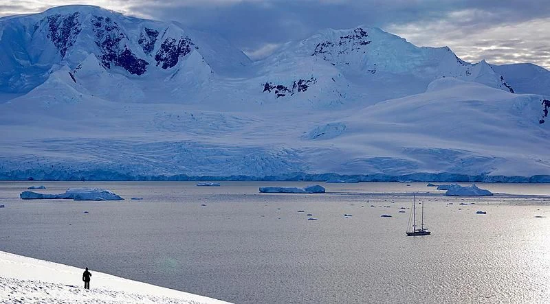 a person walking on a beach with a large mountain in the background aboard ROSEHEARTY Yacht for Charter