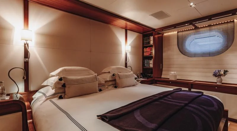 a room with a bed and a book shelf aboard ROSEHEARTY Yacht for Charter