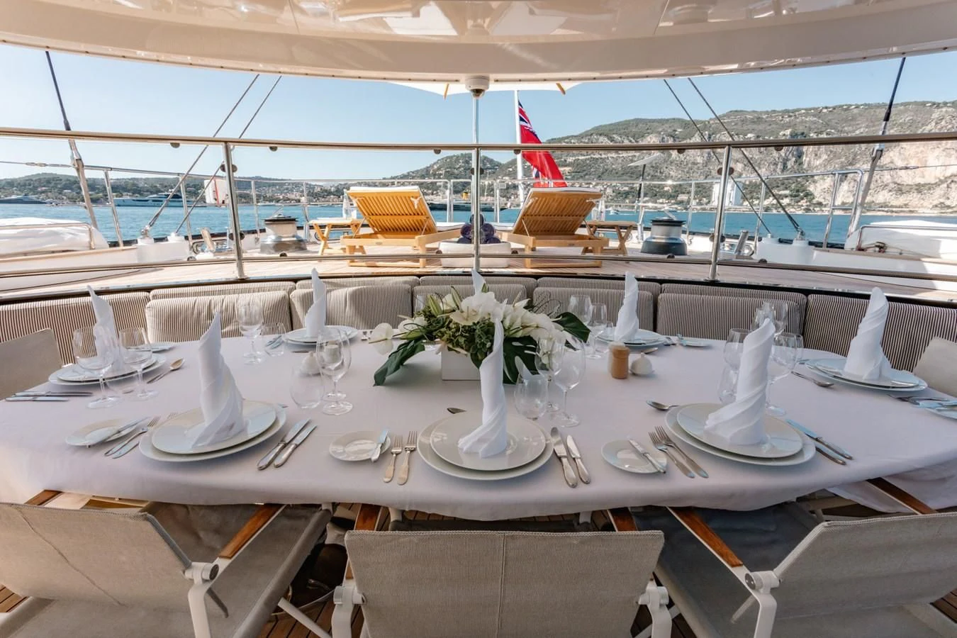 a table set with a red and white tablecloth and chairs with a view of the water and aboard ROSEHEARTY Yacht for Charter