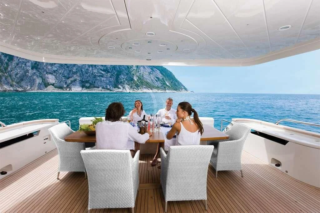a group of people sitting on a couch on a deck overlooking a large body of water aboard NASEEM Yacht for Sale