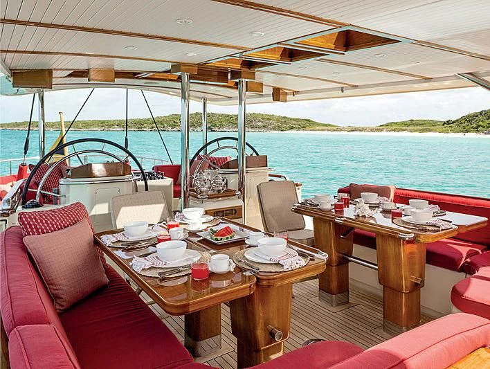 a table with chairs and a boat in the water aboard SMITH Yacht for Sale