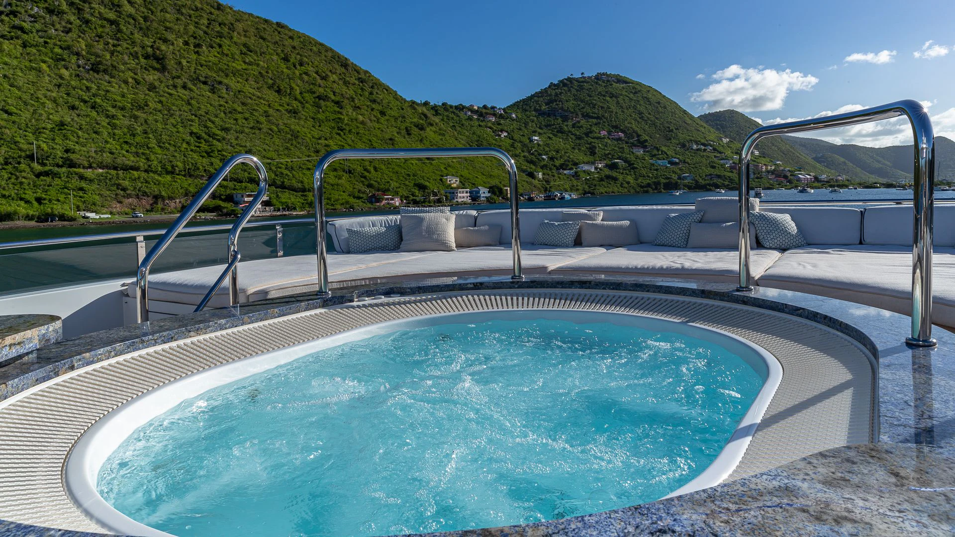 a swimming pool with a large blue glass wall and trees in the background aboard MILESTONE Yacht for Sale