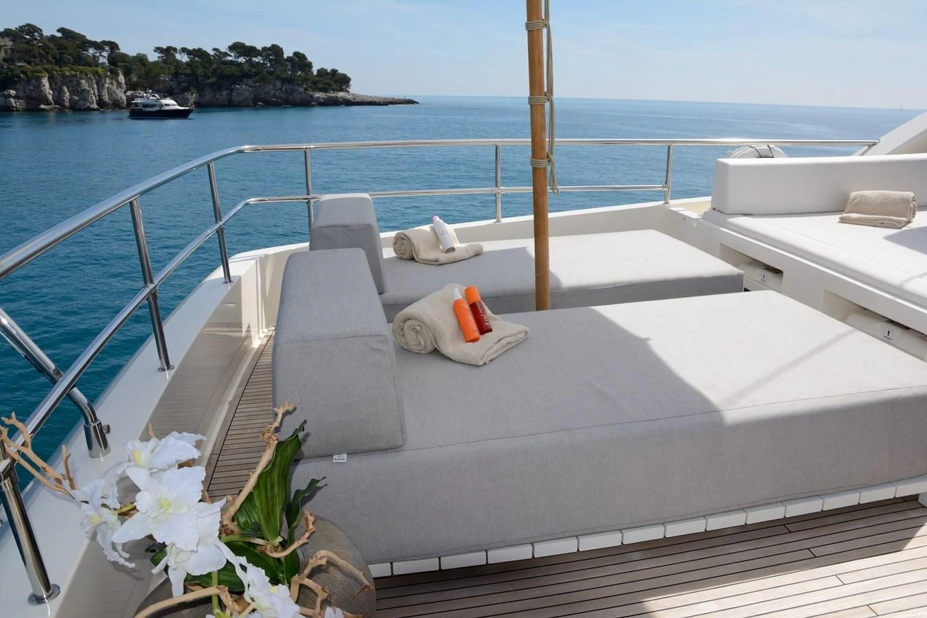 a white lounge chair on a balcony overlooking a body of water aboard HEAL Yacht for Sale