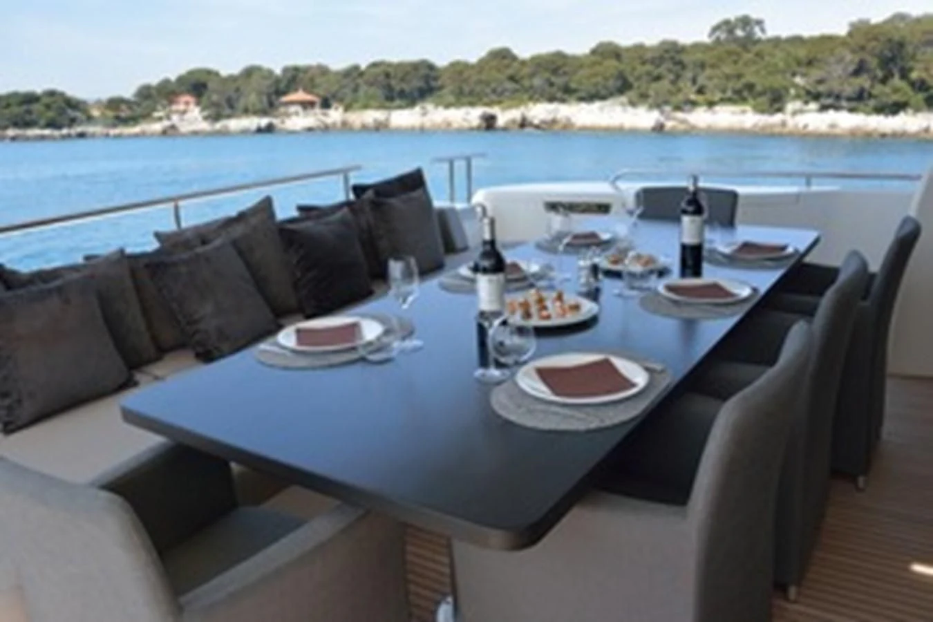 a table with plates and bottles on it by a large body of water aboard HEAL Yacht for Sale