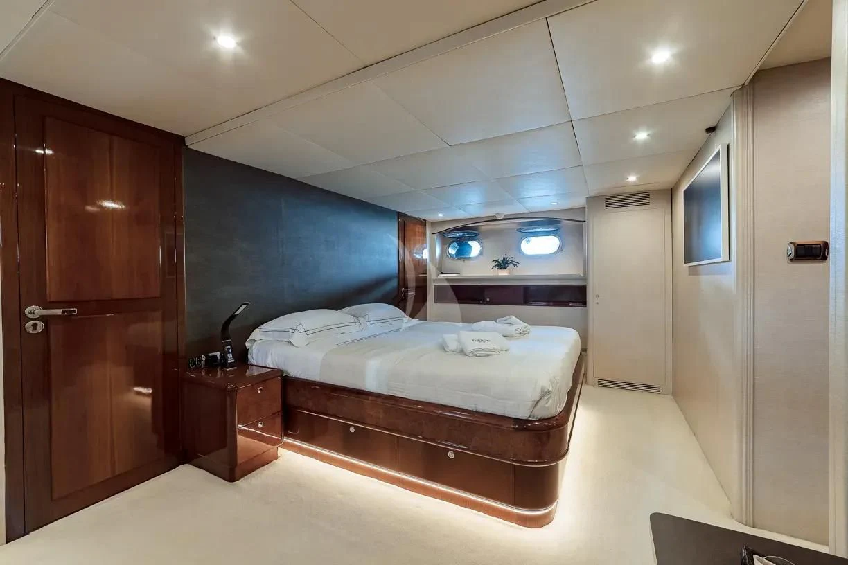 a bedroom with a bed and a wood cabinet aboard THEION Yacht for Sale