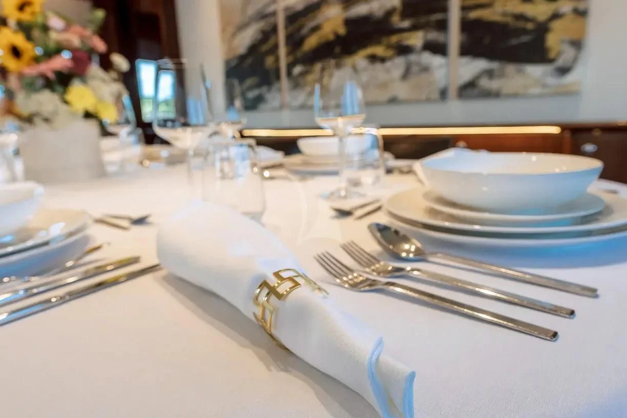a table with empty plates and silverware aboard THEION Yacht for Sale