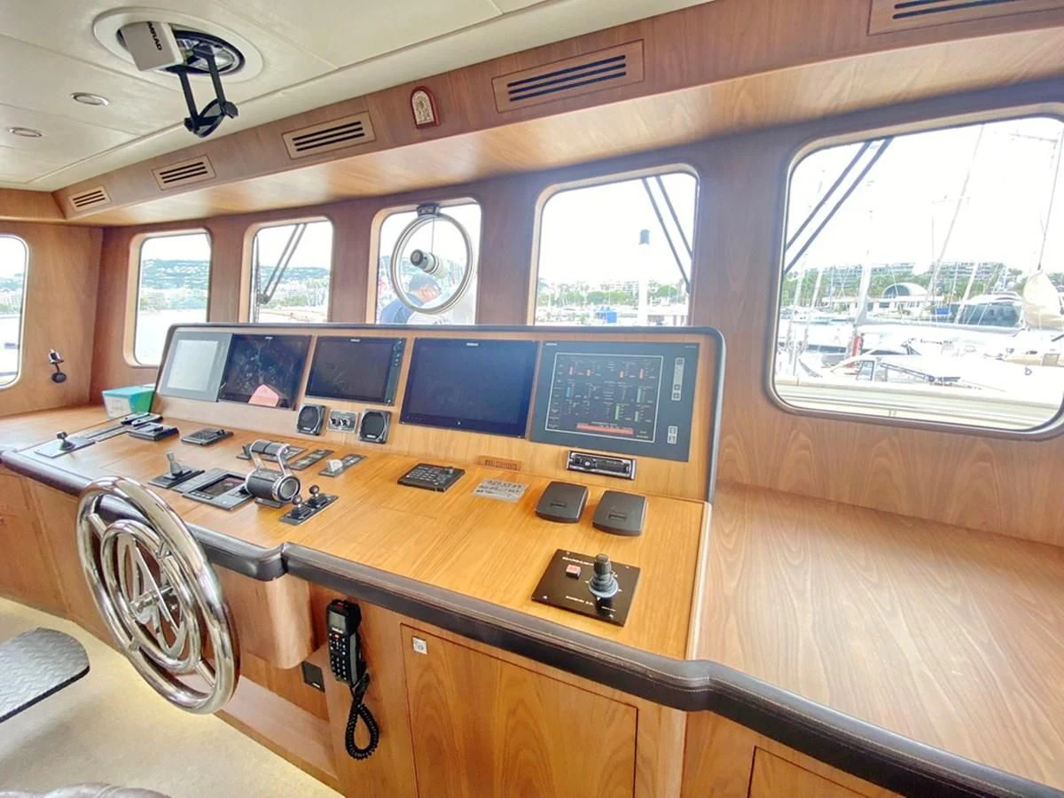 a wooden desk with a computer and other electronics on it aboard O Yacht for Sale
