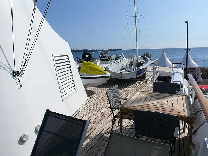 a deck with a table and chairs on it and boats in the water aboard ALTER EGO Yacht for Sale