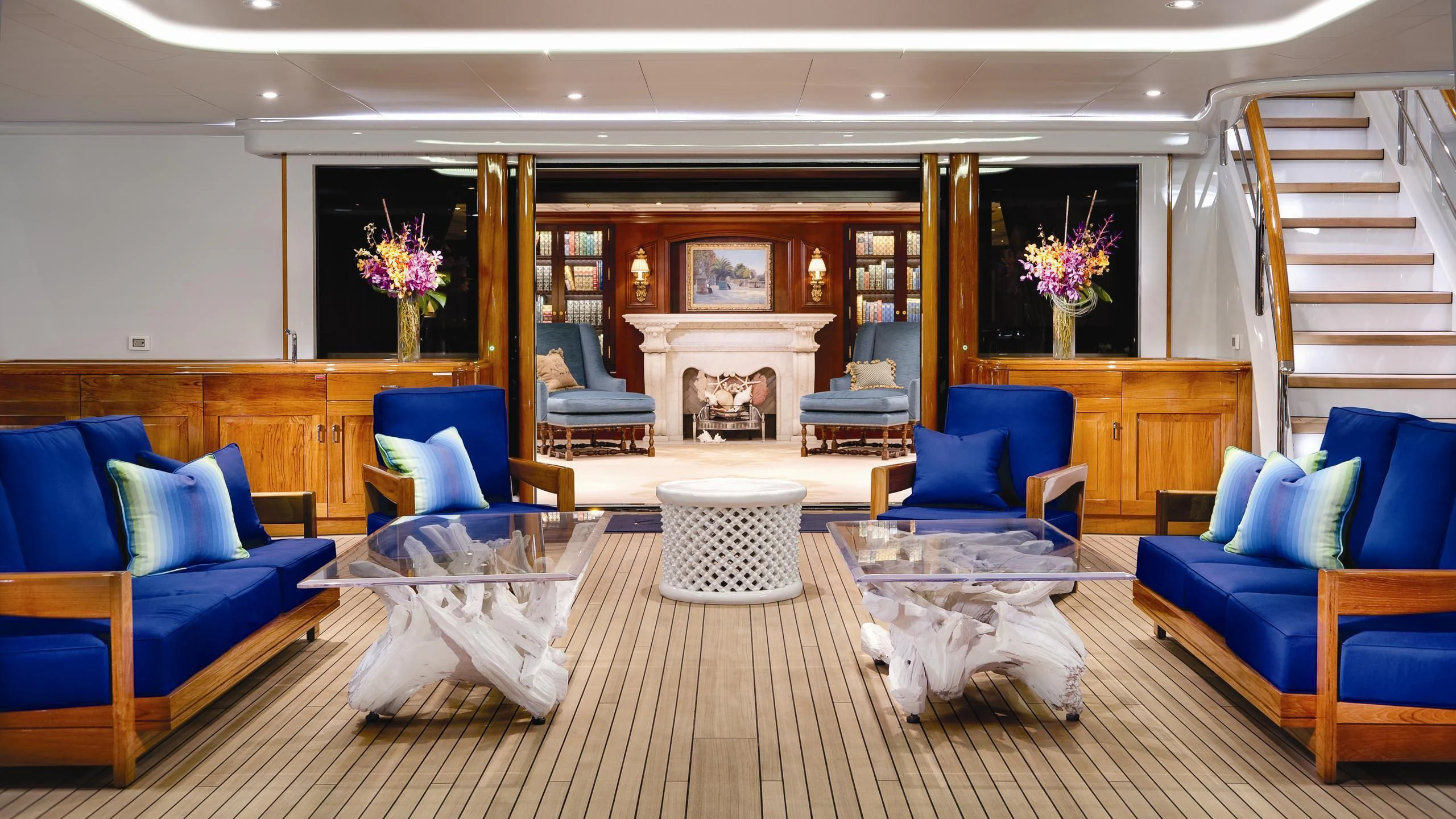 a living room with blue couches and a fireplace aboard AQUILA Yacht for Sale