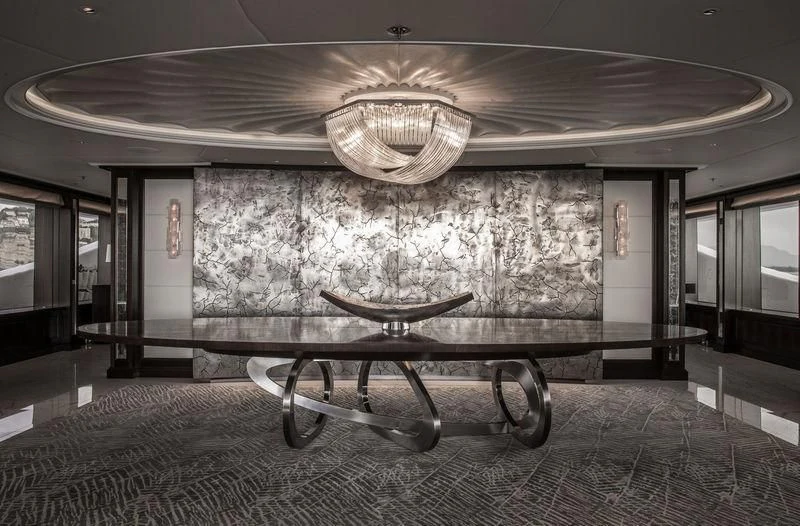 a large room with a chandelier and a table aboard AQUILA Yacht for Sale