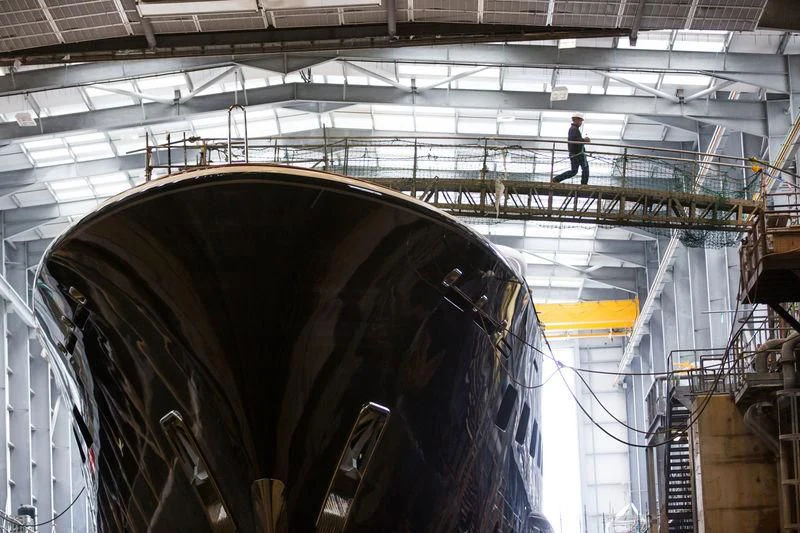 a person standing on a large metal structure in a factory aboard AQUILA Yacht for Sale